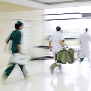 Photo of blurry figures in a healthcare setting rushing through the hallway