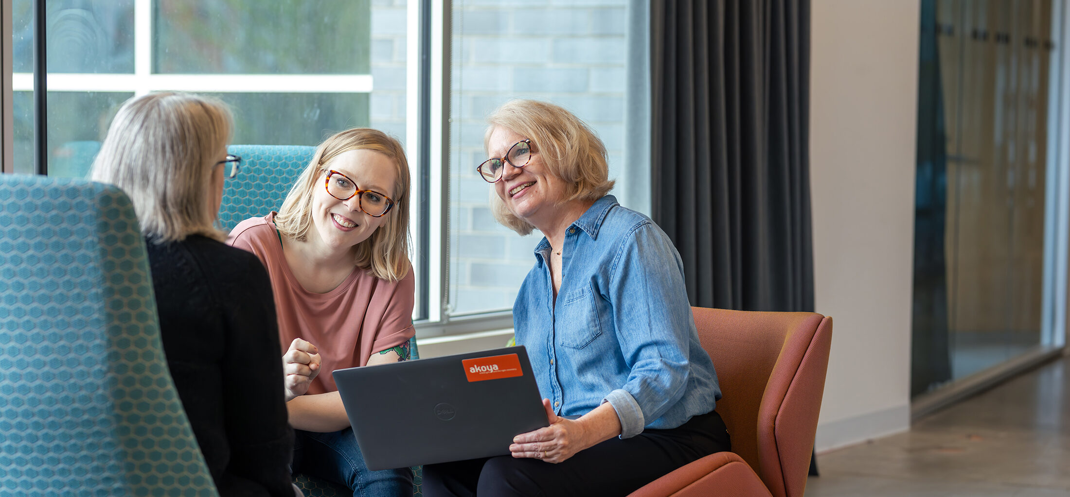 three employees in discussion around a laptop